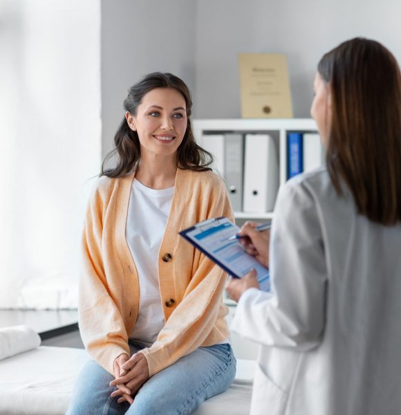 medicine, healthcare and people concept - female doctor with clipboard talking to smiling woman patient at hospital